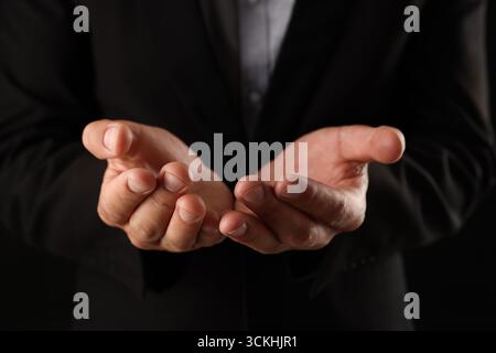 Man holding something on black background, closeup Stock Photo