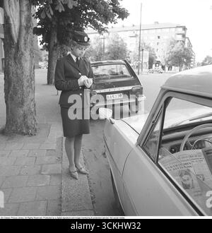 It costs money to park incorrectly. A woman works as a traffic warden and parking attendant, issuing parking fines to a motorist who has parked improperly or failed to pay for parking time. Stockholm. 1968. Kristoffersson ref DX48-4. Stock Photo