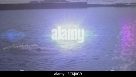 Water surface rippling under bright sunlight at reservoir horizon, with multicolored lens flare Stock Photo