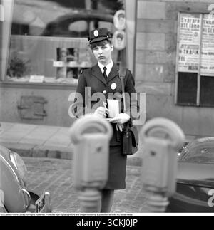It costs money to park incorrectly. A woman works as a traffic warden and parking attendant, issuing parking fines to a motorist who has parked improperly or failed to pay for parking time. Stockholm. 1963 Stock Photo