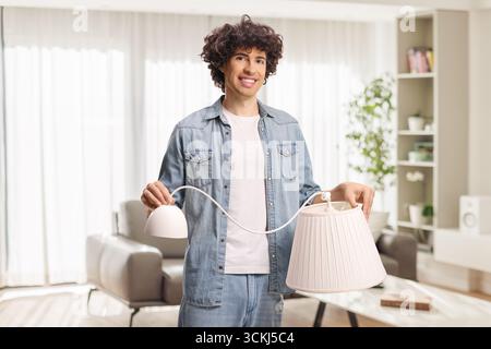 Young man holding a white pendant lamp in a living room Stock Photo