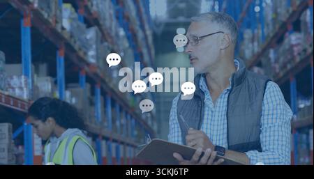 Recording warehouse manager entering inventory on clipboard in warehouse aisle with racks and boxes Stock Photo