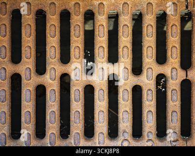 Rusty metal drainage grate with rectangular openings over dark background . High quality photo Stock Photo