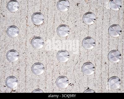 Close up of tactile paving with metal studs on concrete surface for blind guidance . High quality photo Stock Photo