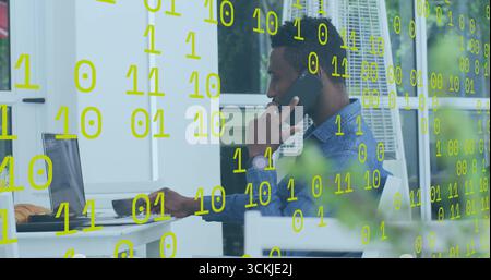 Man typing on laptop and talking on smartphone on terrace, with floating binary code Stock Photo