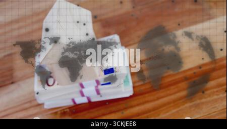 Displaying stacks of euro banknotes with colored straps on wood tabletop, showing world map overlay Stock Photo