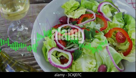 Featuring white bowl of fresh salad on rustic wooden table, with wine glass and oil cruet Stock Photo