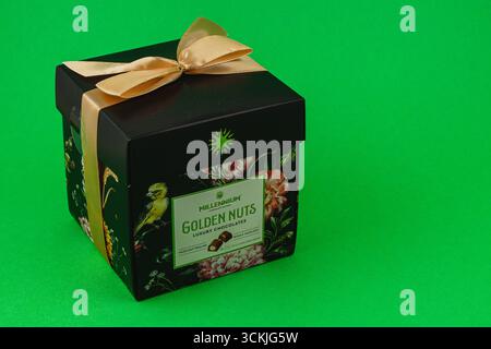 Ukraine Lviv 20.08.25A black box adorned with floral designs and a gold ribbon contains luxury chocolates. The vibrant green backdrop enhances the ele Stock Photo
