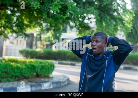 Young African man touching his head with a confused and worried expression, isolated on white background. Concept of stress, problem solving, and diff Stock Photo