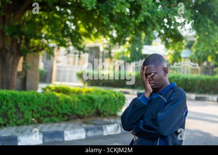 Young African man covering his face with a confused and worried expression, isolated on white background. Concept of stress, problem solving, and diff Stock Photo