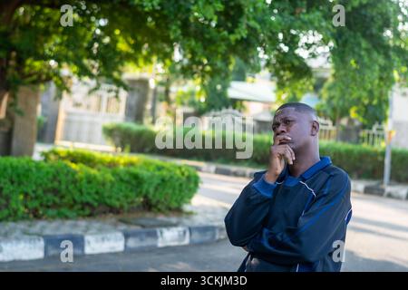Young African man touching his jaw thinking with a confused and worried expression, isolated on white background. Concept of stress, problem solving, Stock Photo
