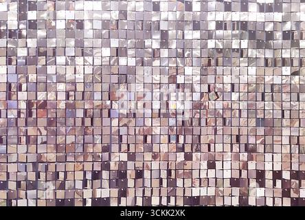 A decorative wall with an ornament of shiny mirrored lilac and pink squares. The background is made of square mirrored tiles. Stock Photo