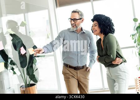 Professional coworkers brainstorming together in a modern workplace setting with teamwork and positive engagement Stock Photo