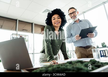 Two diverse business professionals collaborating in a modern office environment, exuding teamwork, professionalism, and creativity Stock Photo