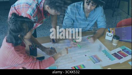 Collaborating professionals pointing, marking, leaning over office table, with mockups, markers Stock Photo