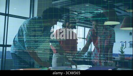 Collaborating professionals leaning over table in sunlit office, with laptops tablet documents Stock Photo
