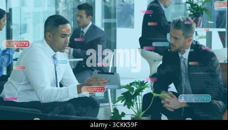 Discussing strategy two suit-clad professionals in corporate lounge, with tablet and plant Stock Photo