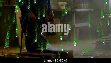 Metalworker wearing protective gear heating block using two torches in workshop, green code overlay Stock Photo