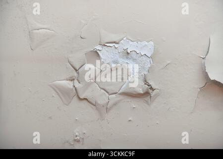 Peeling paint and cracked plaster wall with moisture damage. Stock Photo