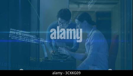 Leaning IT technician and engineer examining laptop in server room, with server rack and cables Stock Photo