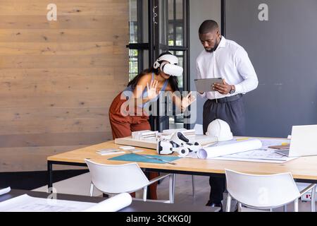 Diverse coworkers collaborating at design studio, using vr headset over blueprints, tablet Stock Photo
