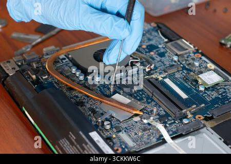 A technician is repairing the motherboard of a laptop computer. Stock Photo