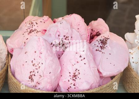 August 28, 2025, Bruges, Belgium — A basket of large pink meringues decorated with chocolate sprinkles displayed in a shop window. Stock Photo