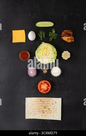Flat lay of fresh shawarma ingredients with lavash on dark background, top view Stock Photo