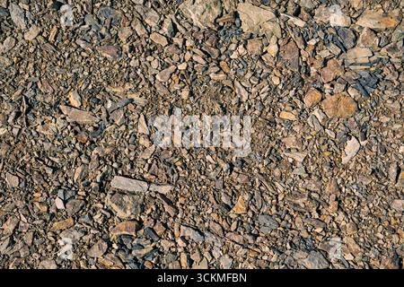 Brown rocky ground with earthy texture and small stones, natural outdoor surface background for geology, construction, and rugged material design. Stock Photo