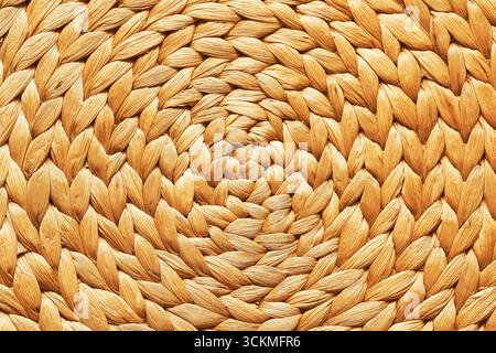 Braided straw texture background. Round woven natural material surface. Rustic handmade craft detail with organic pattern. Stock Photo