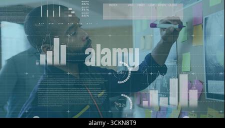 Man in blue sweater marking sticky notes with purple marker on partition in office, data analysis Stock Photo