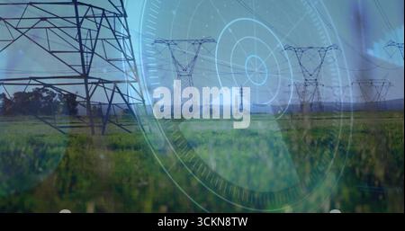 Displaying steel lattice transmission towers spanning grass field, overlaying circular digital HUD Stock Photo