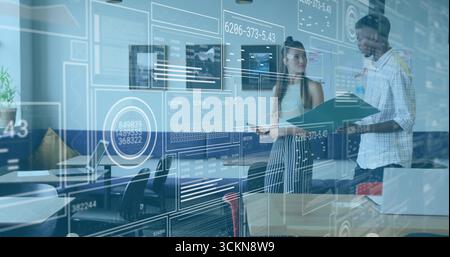 Discussing two coworkers analyzing AR data interface in modern office, with laptop and tablet Stock Photo