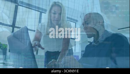 Collaborating coworkers examining data overlays on glass in office in business attire with laptop Stock Photo
