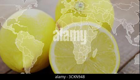 Featuring three bright yellow lemons sitting on wooden tabletop, with faint white world map overlay Stock Photo