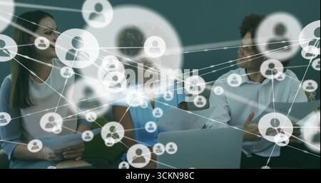Collaborating professionals reviewing network overlay in office lounge, with laptop and documents Stock Photo