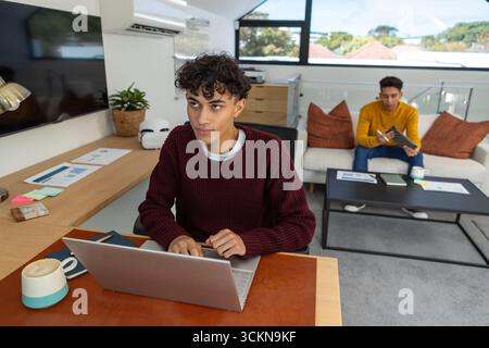 Diverse coworkers working together in loft-style office with laptop, sticky notes, coffee mugs Stock Photo