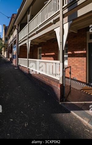 Brick building with horizontal wooden balcony, offering an architectural insight into urban residential design on a clear day, Millers Point, Sydney Stock Photo