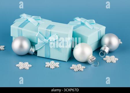 Blue gift boxes with ribbons on blue background. Gift boxes,   Christmas balls and snowflakes on blue. Stock Photo