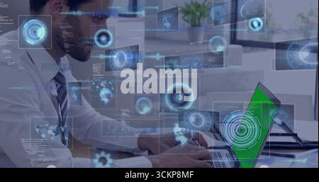 IT professional typing on green-screen laptop at office desk, with floating data charts Stock Photo