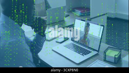 Displaying silver laptop showing coworker speaking during virtual call at desk, with smartphone Stock Photo