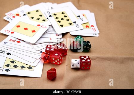 Extended poker cards, several dice of different colors and sizes on a cardboard-like surface. Stock Photo