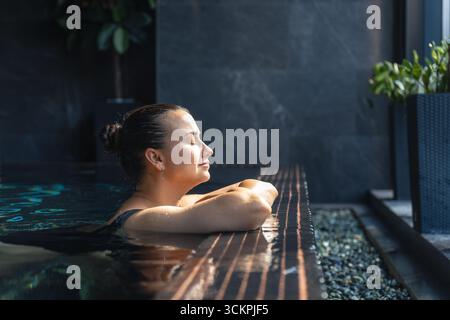 Woman relaxing in spa pool by the window. Quiet mindful pause. Stock Photo