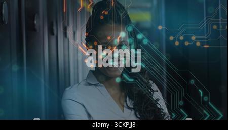 Smiling IT engineer wearing shirt in server room, with blinking LEDs and circuit overlay Stock Photo