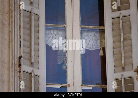 Antique wooden window with shutters and vintage cutwork curtains in the Old Venetian Town of Corfu island in Greece. Stock Photo