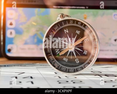 A close-up shot of a person holding a vintage-style compass with a metallic finish and clear markings for cardinal directions (N, S, E, W) and degree Stock Photo