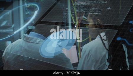 Analyzing virtual interface, two technicians in lab coats adjusting network cables in data center Stock Photo