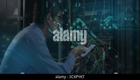 Crouching network engineer wearing tie configuring servers with cables in data center, copy space Stock Photo
