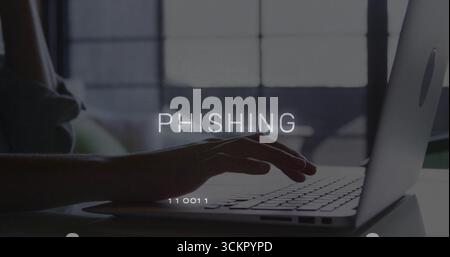 Hovering hand typing on laptop keyboard at home office desk, with overlay text PHISHING Stock Photo