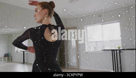 Practicing lone dancer wearing black leotard stretching at ballet studio barre, copy space Stock Photo